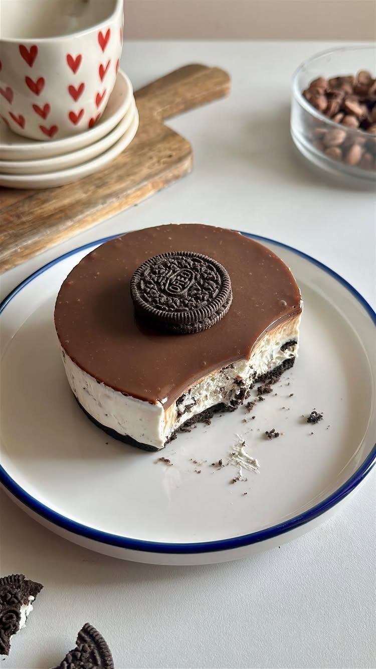 Small chocolate topped cheesecake with a sandwich cookie on a white plate