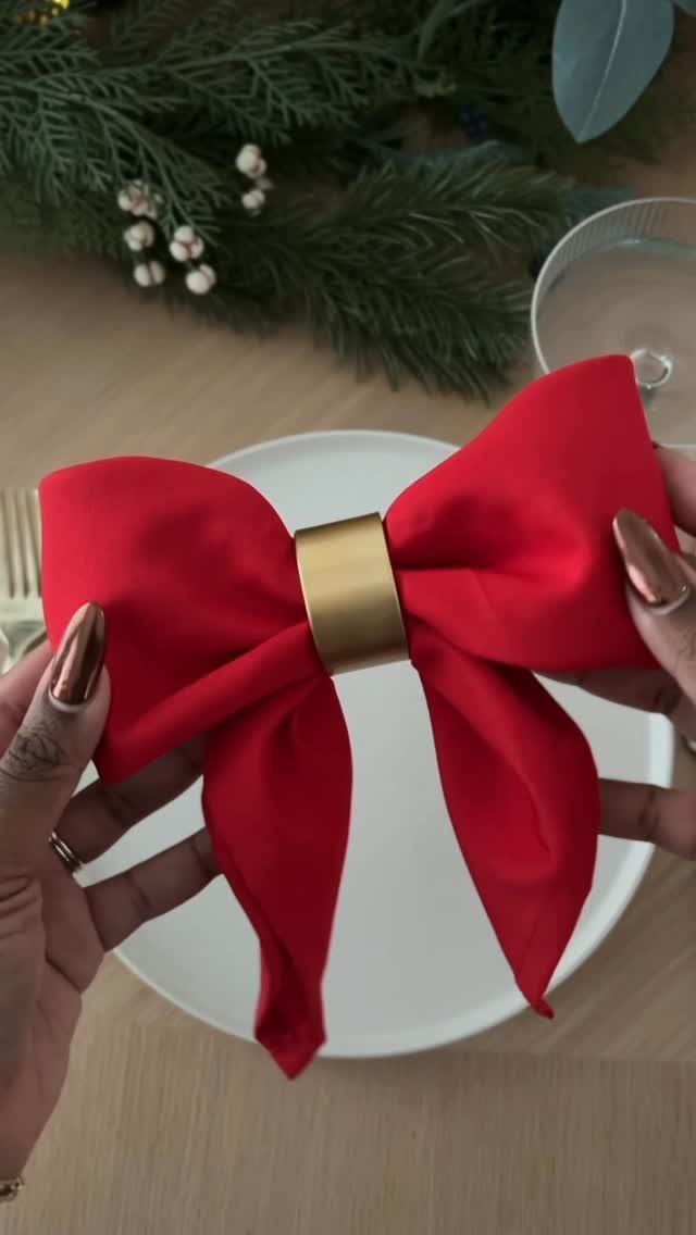 Red fabric napkin folded as a bow with a gold ring on a plate