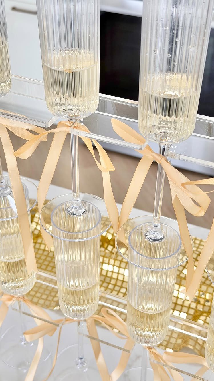 Champagne flutes with gold ribbons on a tiered stand over gold sequins