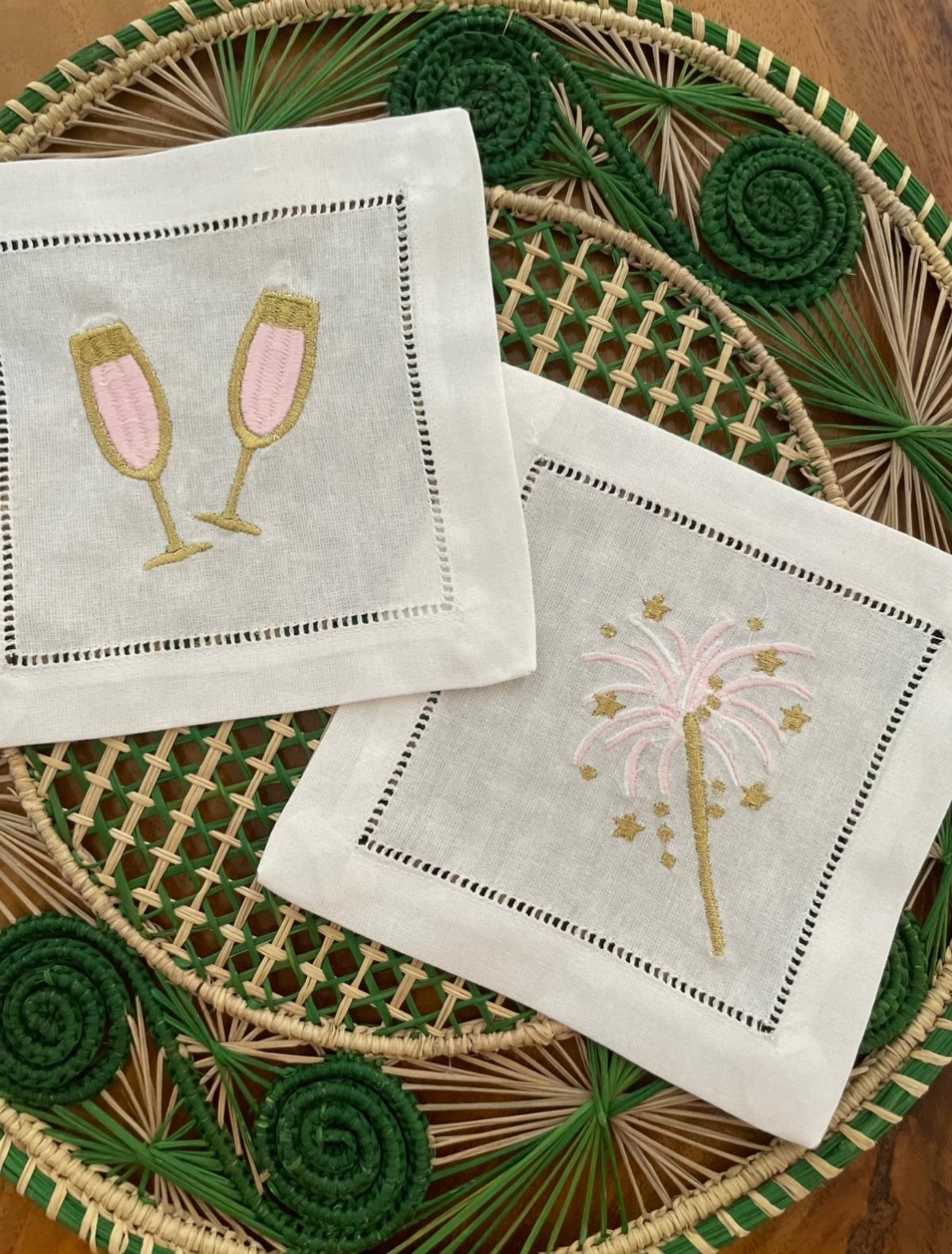 White embroidered napkins with champagne glasses and fireworks on a woven green charger.