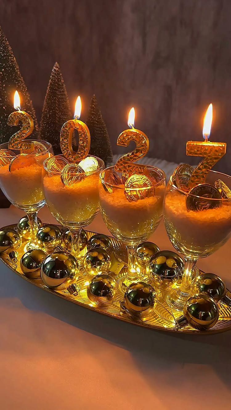 Champagne glasses with gold number candles and ornaments on a gold tray