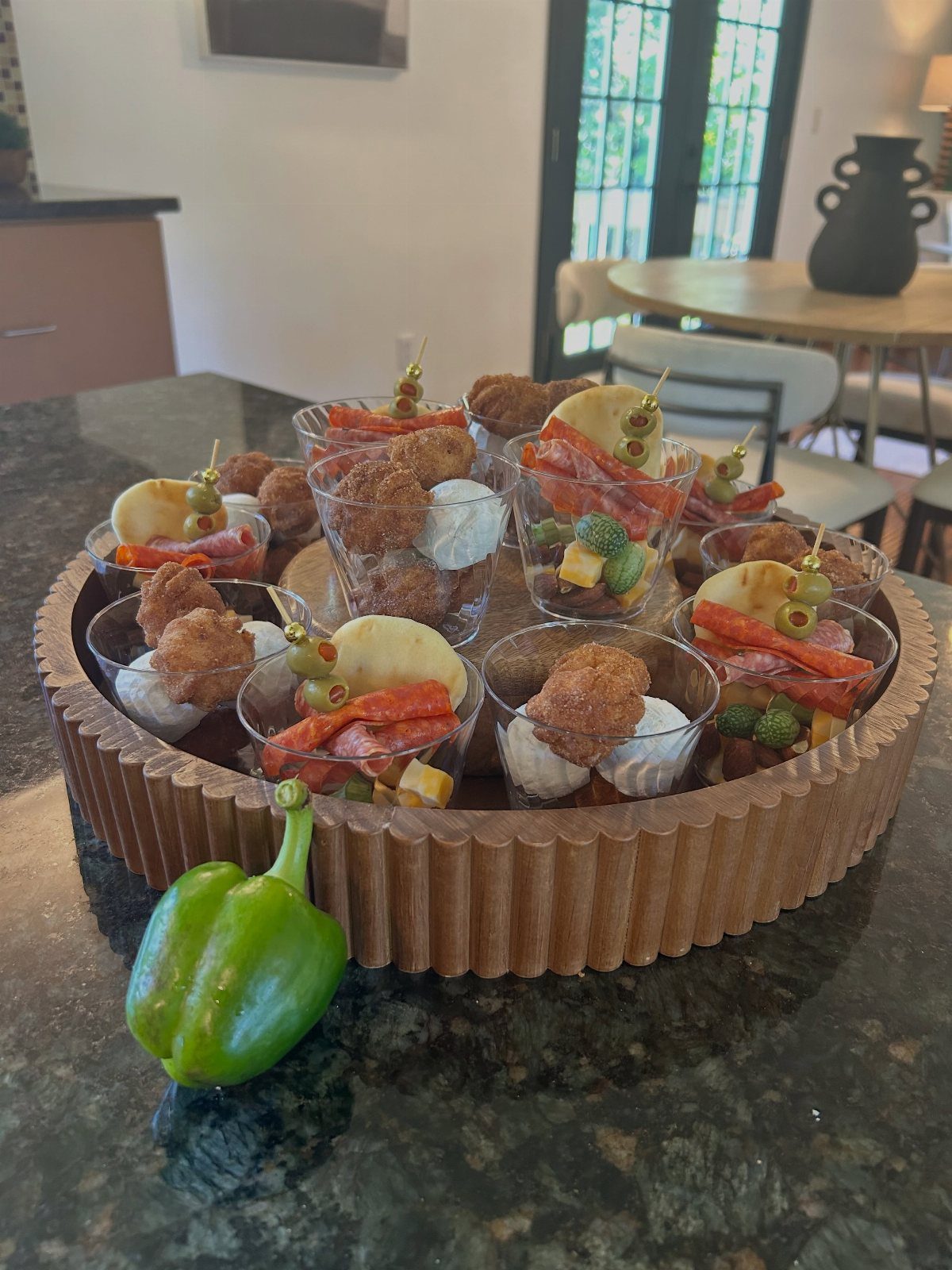 Charcuterie cups with meats and cheeses on a wooden tray on a countertop