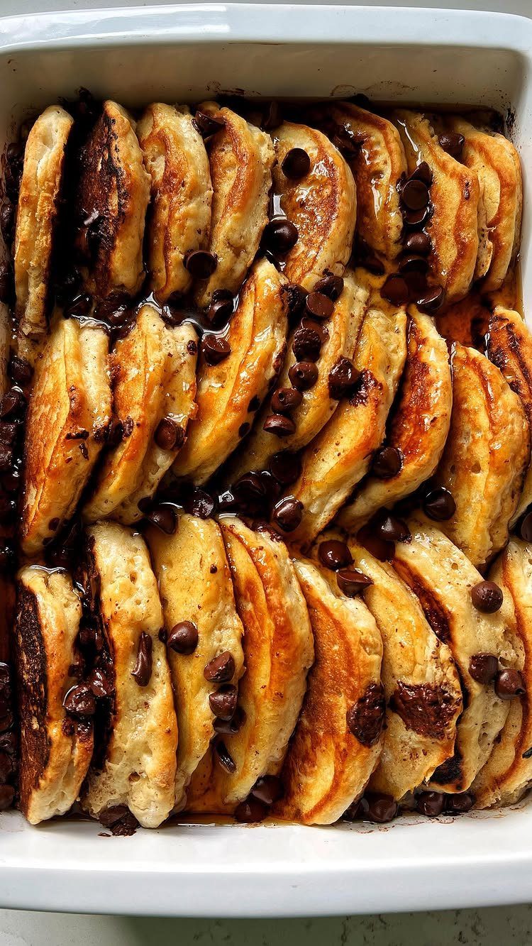 Pancakes with chocolate chips and syrup baked in a white ceramic casserole dish.