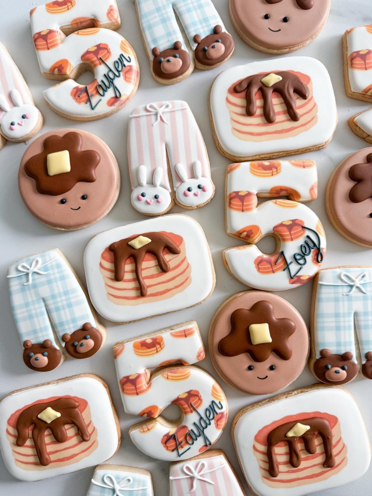 Decorated sugar cookies shaped like pancakes, pajama pants, and the number five.
