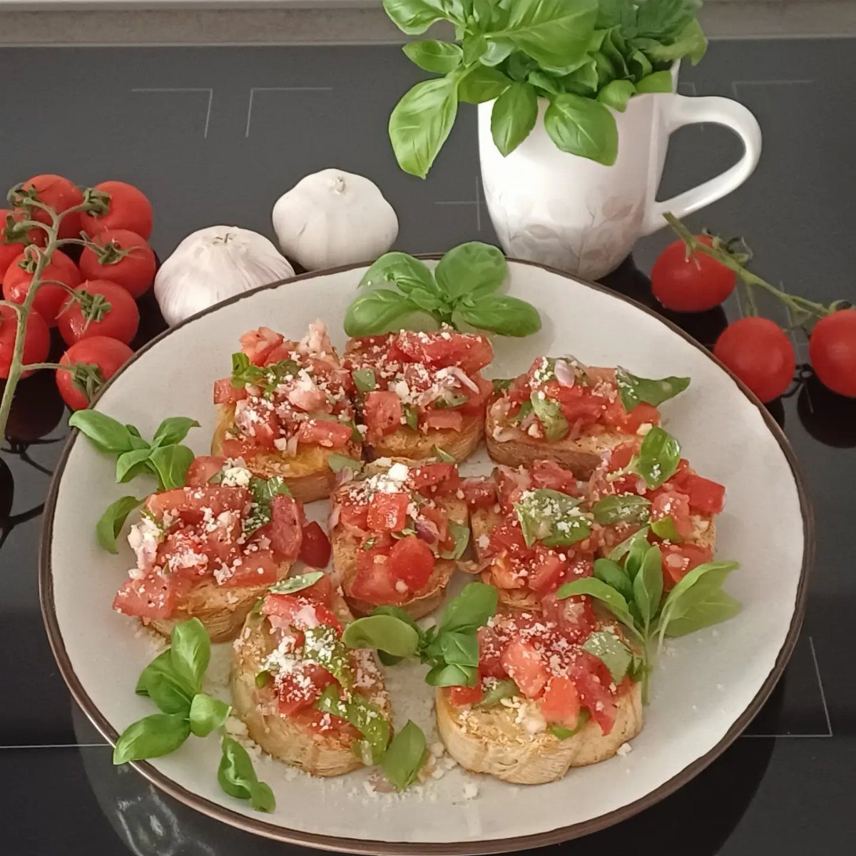Bruschetta topped with tomatoes and basil on a plate with fresh ingredients.