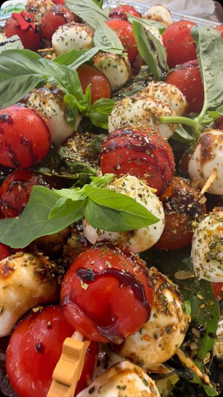 Caprese skewers with cherry tomatoes, mozzarella, and basil drizzled with balsamic glaze.