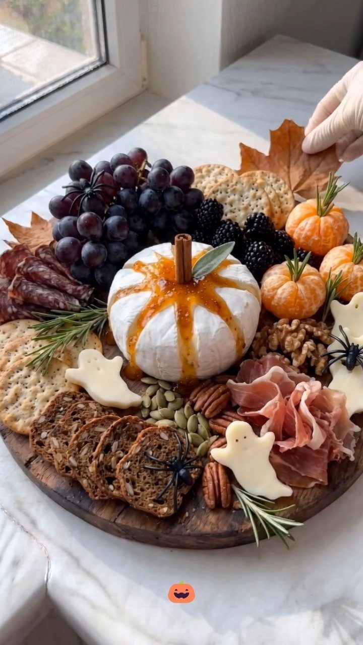 Halloween charcuterie board with pumpkin-shaped Brie, ghost cheese, grapes, and cured meats.
