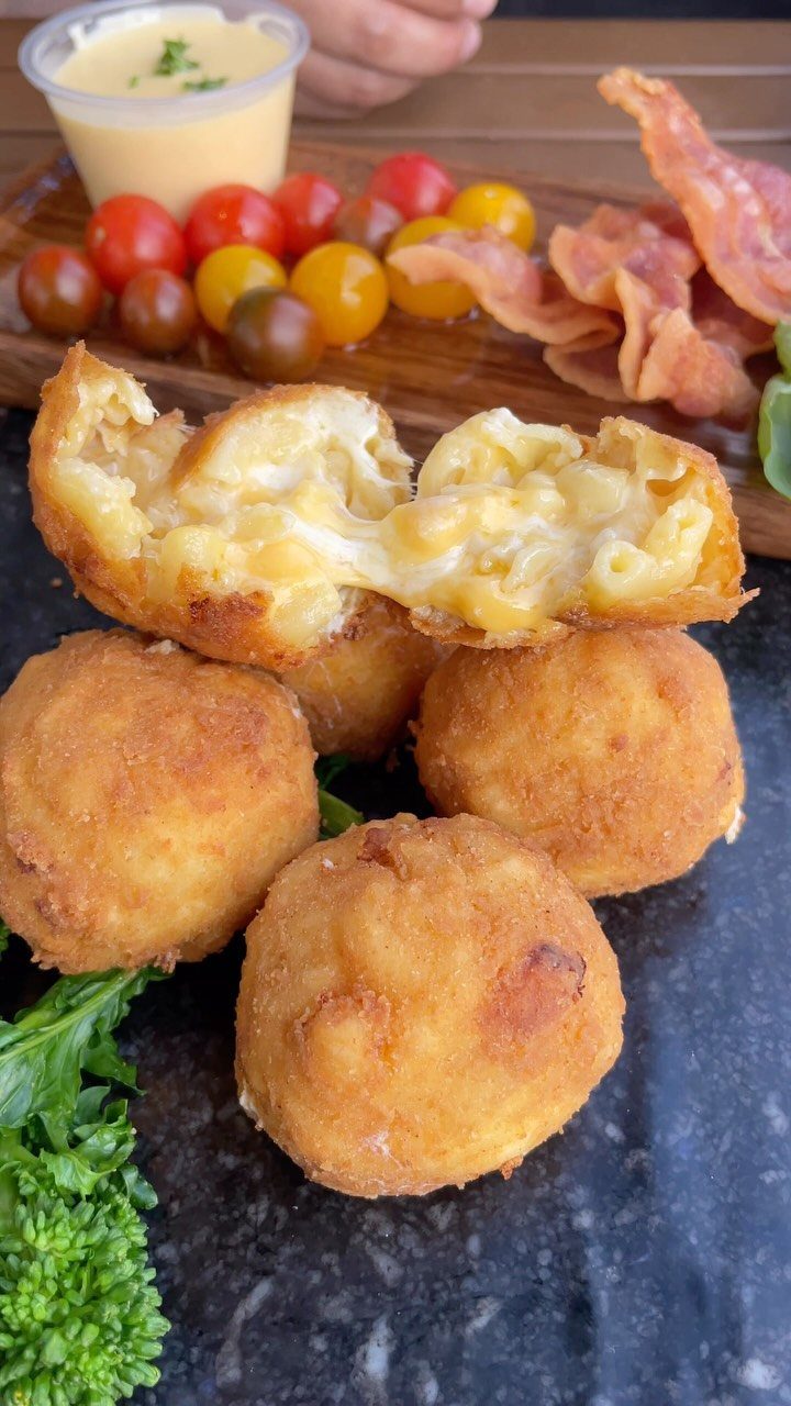 Fried mac and cheese balls with one split open showing creamy macaroni filling.