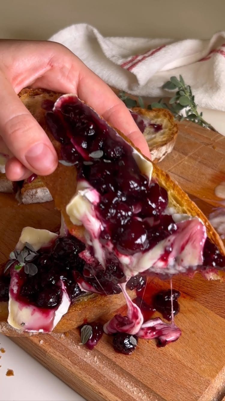Toasted bread topped with melted brie cheese and dark purple berry fruit compote.