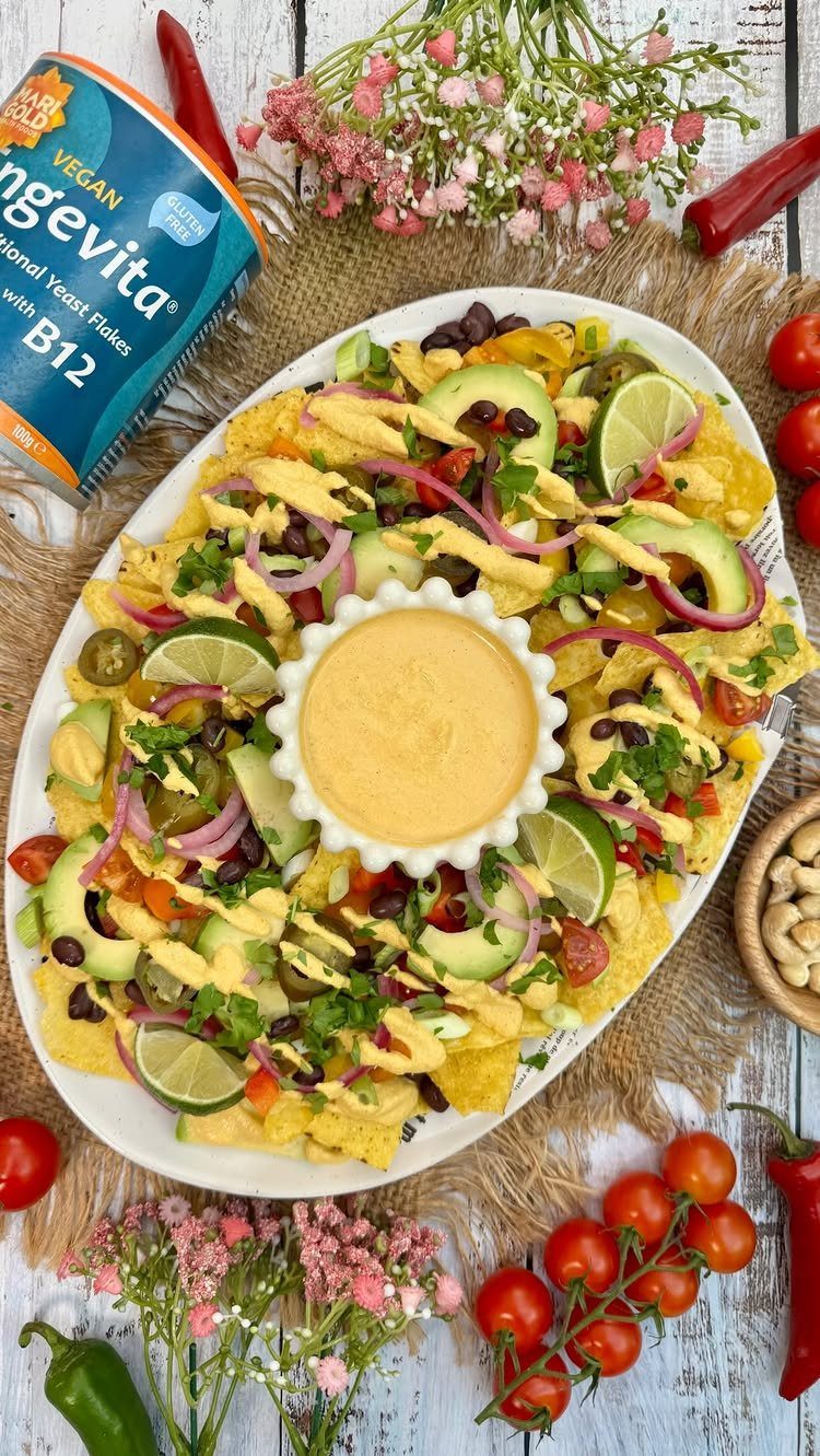 Loaded nachos with avocado, onions, and lime on a platter with dipping sauce.