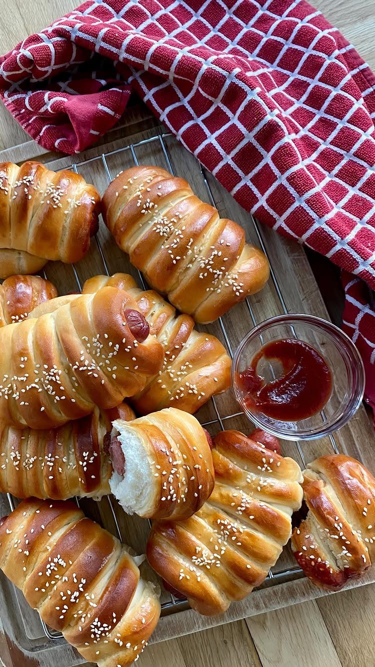 Mini sausages wrapped in golden sesame dough served with a side of ketchup.