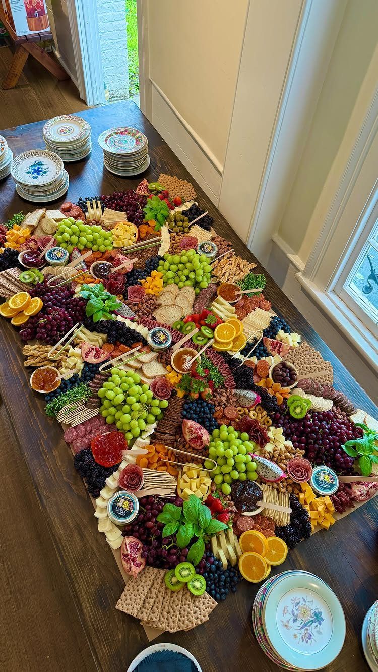 Large spread of assorted cheeses, fresh grapes, berries, and crackers on a table.