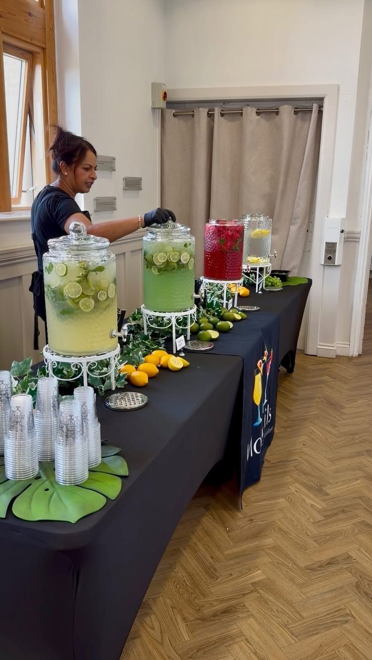 Beverage station with four large glass dispensers filled with colorful fruit drinks.