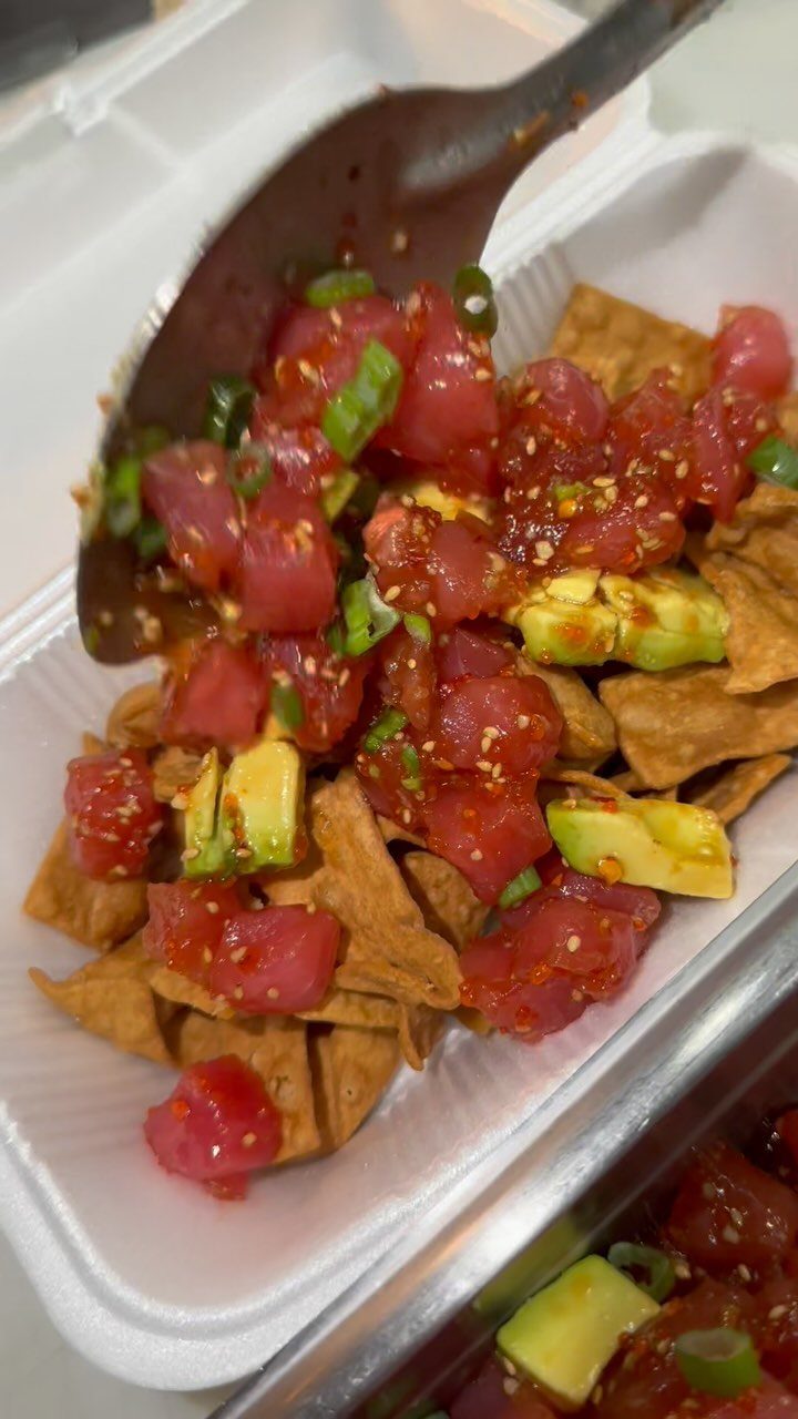 Diced raw tuna and avocado served over crispy tortilla chips in a container.