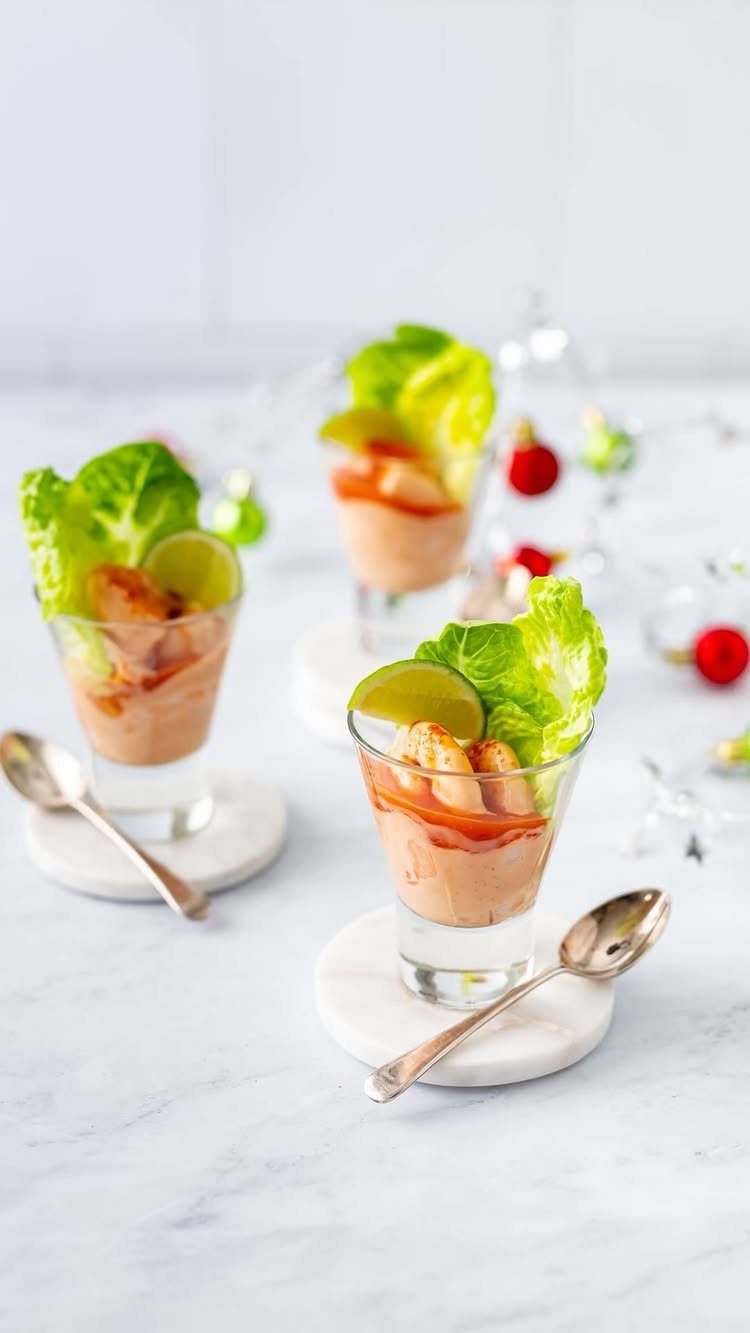 Shrimp cocktail appetizers in small glasses with creamy sauce, lime, and lettuce.