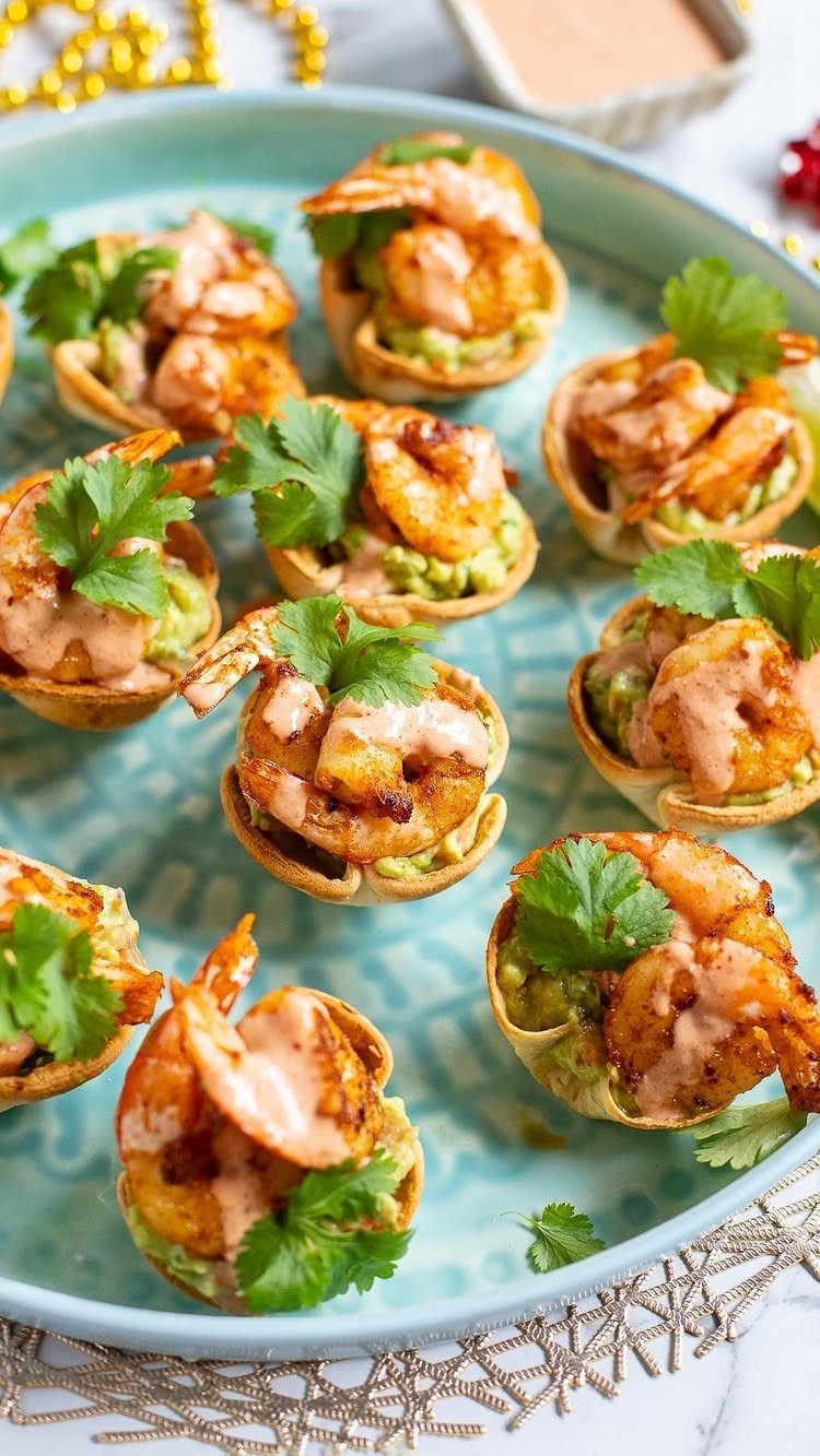Grilled shrimp in tortilla cups with guacamole and sauce on a blue platter
