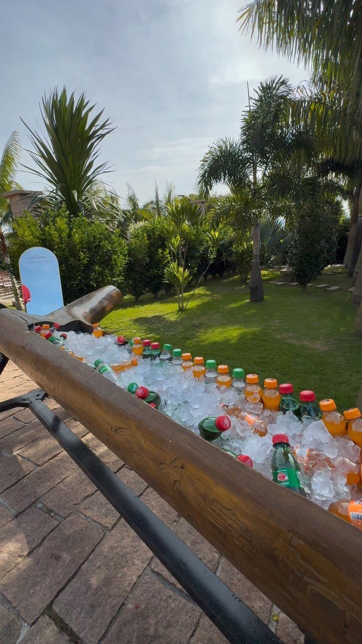 Bottled drinks chilled in a wooden ice trough on an outdoor stone patio.