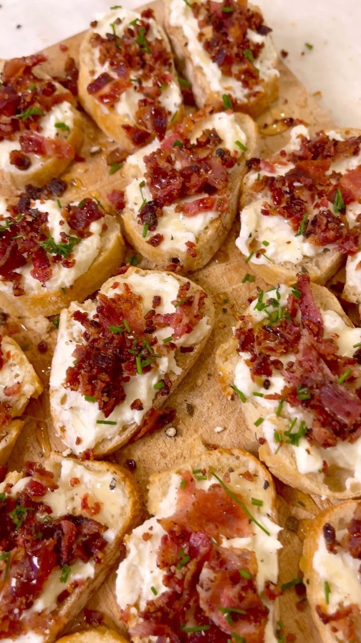 Toasted baguette slices topped with creamy white cheese, crispy bacon, and fresh chives.