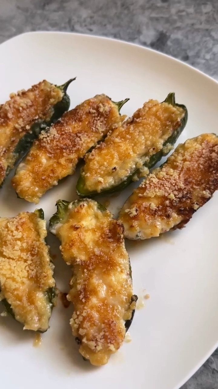 Stuffed jalapeño poppers with golden breadcrumb topping on a white plate