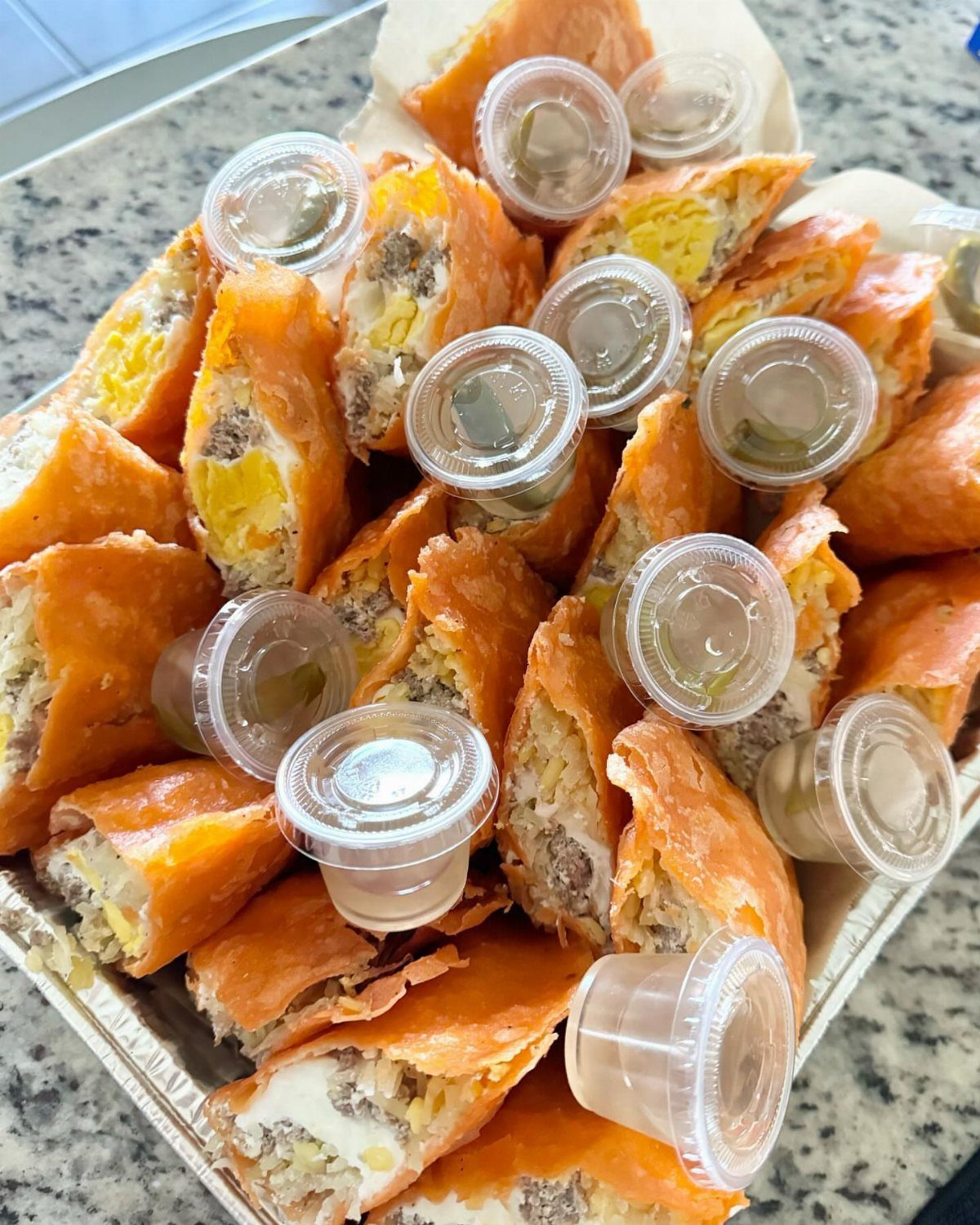Golden-brown puff pastry beef empanadas with melted cheese and small dipping sauce cups.