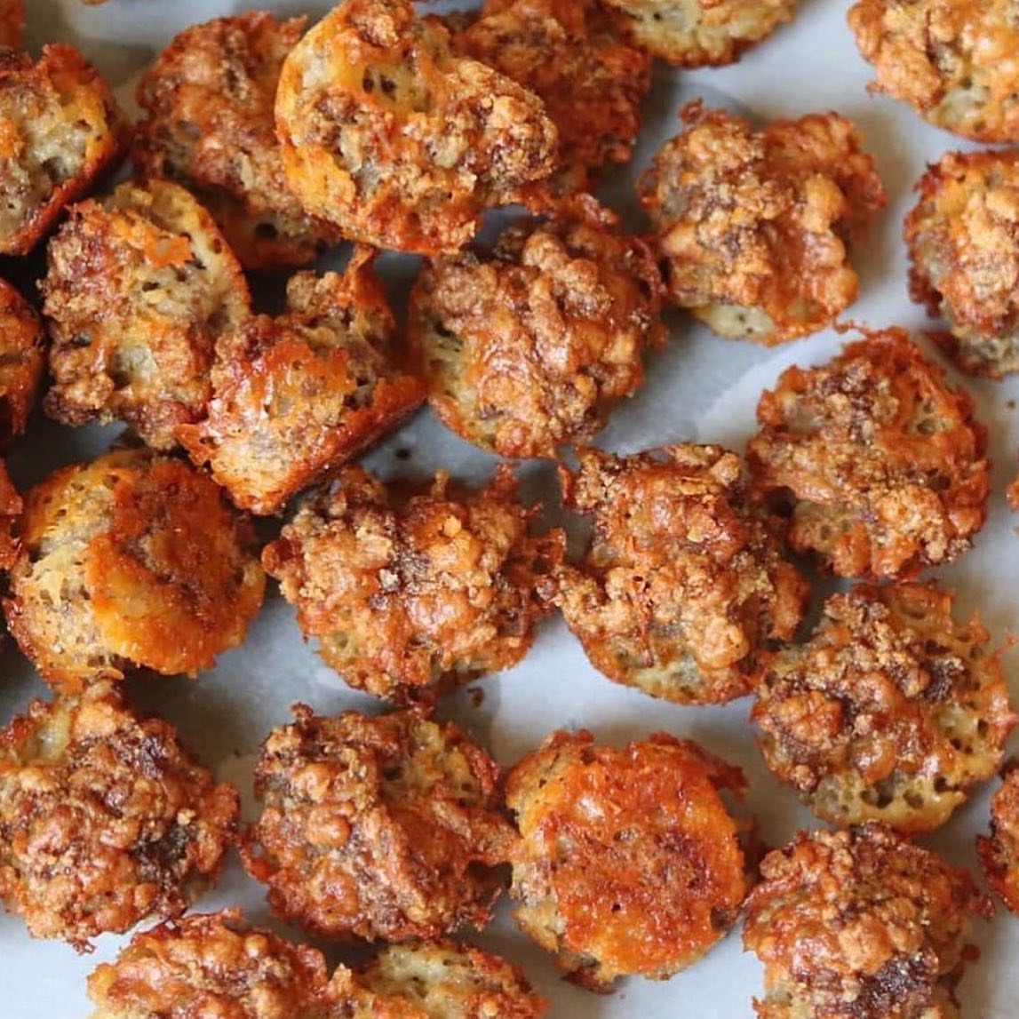 Golden-brown savory sausage balls scattered on white parchment paper.