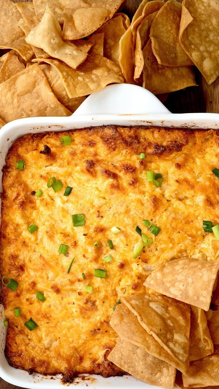 Buffalo chicken dip in a white baking dish served with tortilla chips.