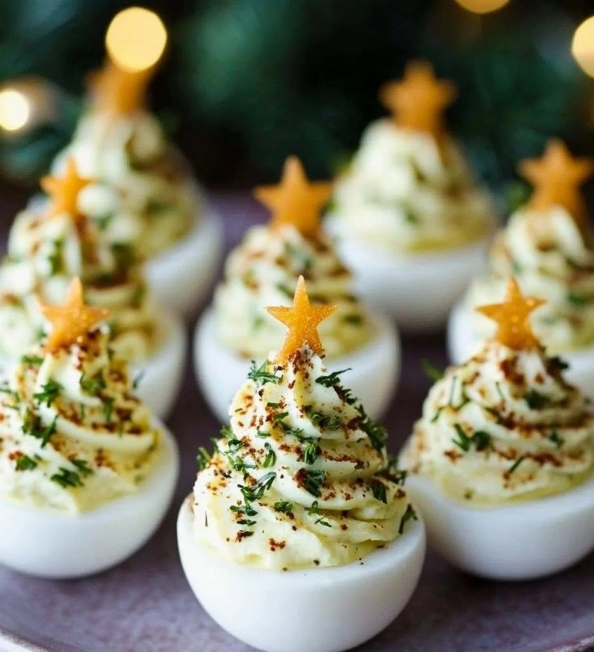 Deviled eggs with piped filling topped with herbs and small orange stars.