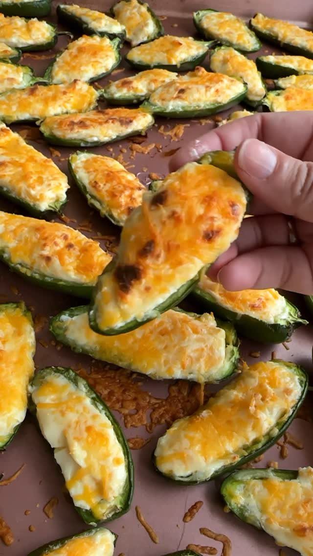 Baked jalapeño poppers filled with melted cheese on a baking sheet.