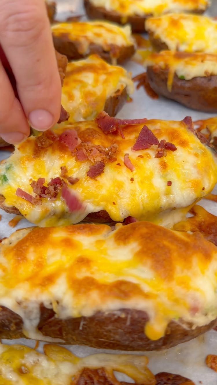 Loaded potato skins topped with melted cheese and bacon on a baking sheet.