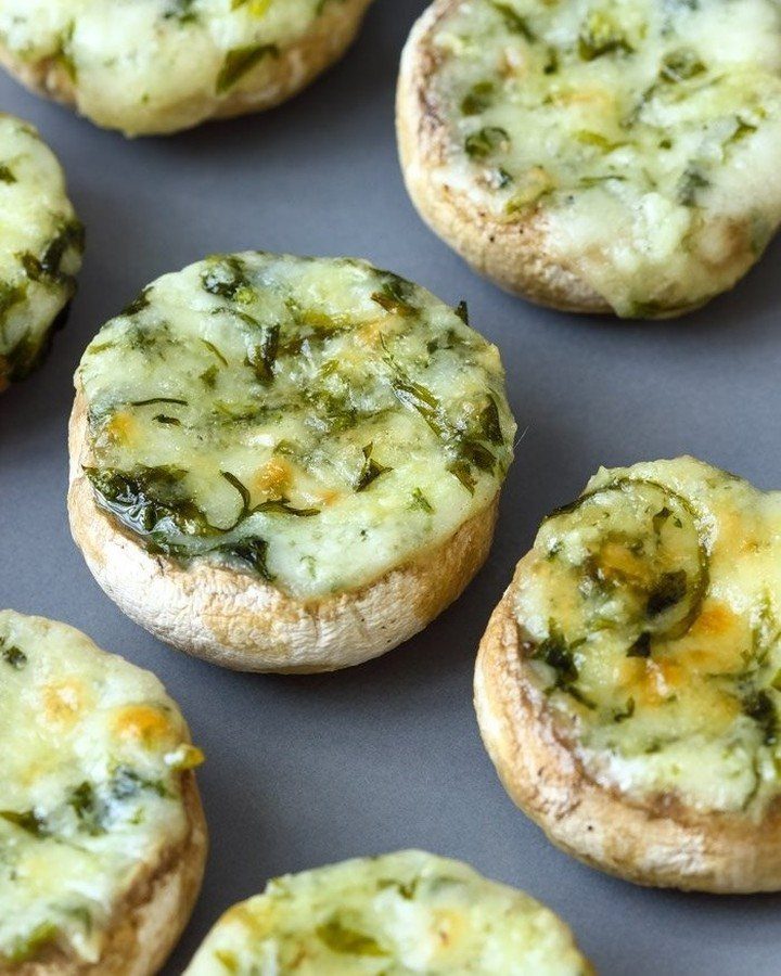Stuffed mushrooms filled with melted cheese and spinach on a grey background