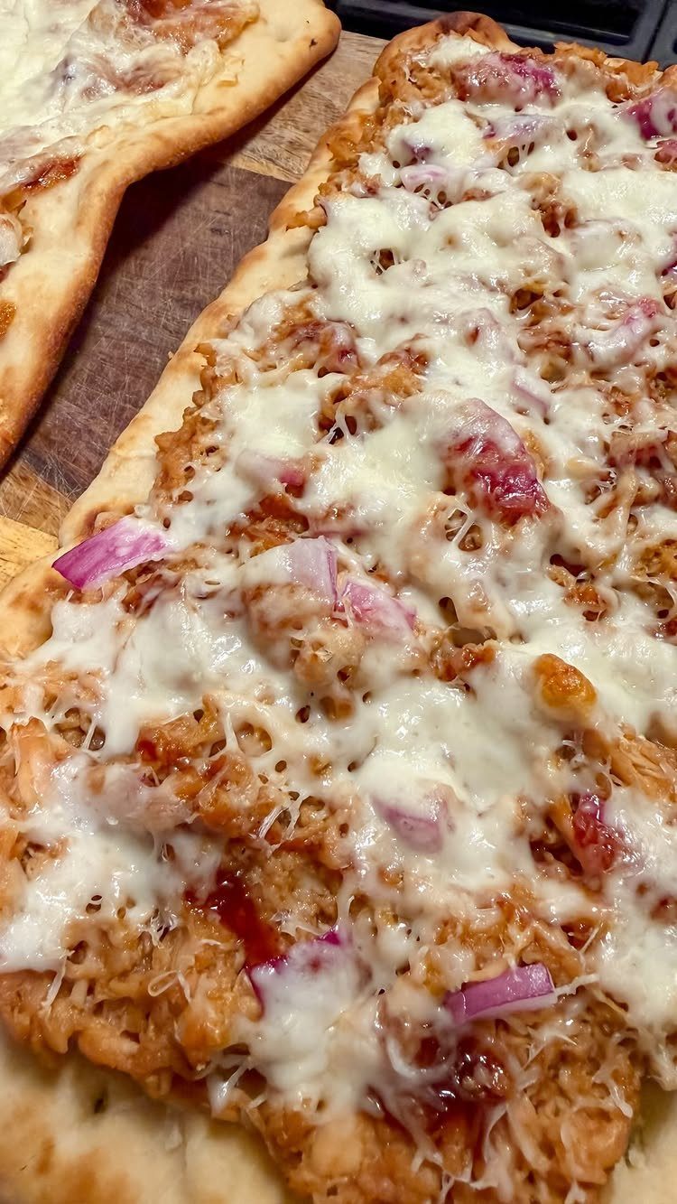 BBQ chicken pizza with melted cheese and red onions on a wooden board