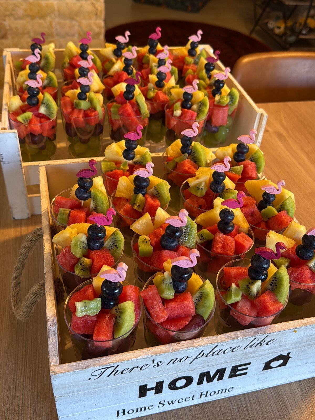 Fruit cups with watermelon, kiwi, and pineapple topped with pink flamingo picks.