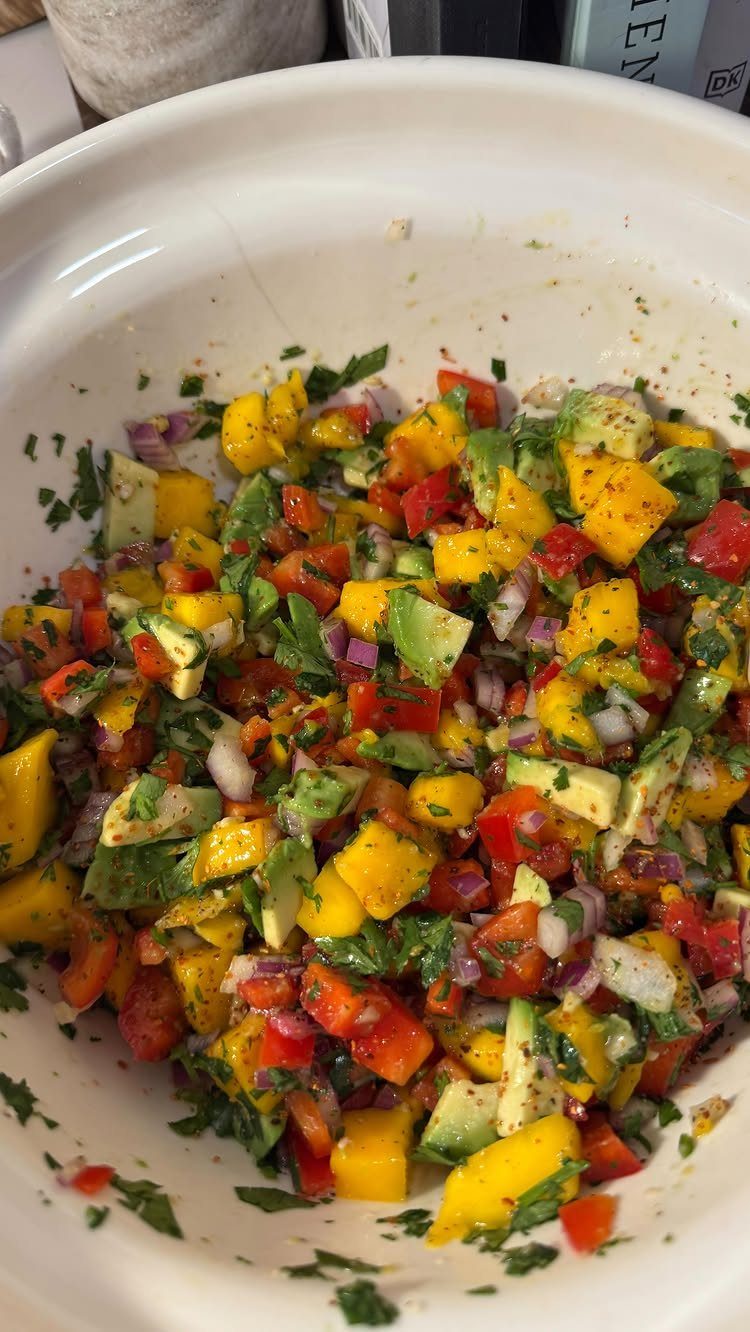 Mango avocado salsa with red peppers and onions in a white bowl.