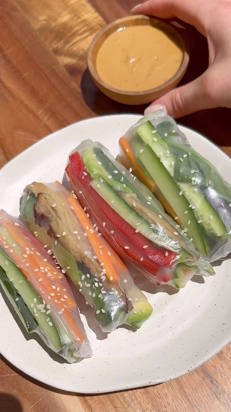 Rice paper rolls with fresh vegetables on a plate with a dipping sauce.