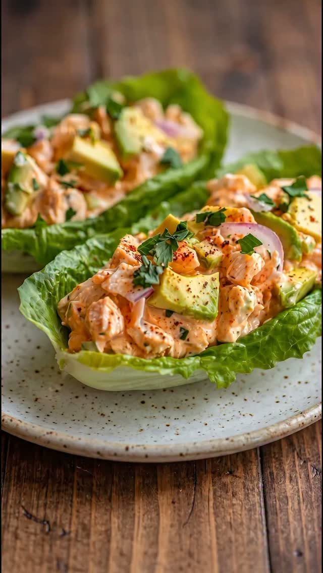 Salsa chicken lettuce wraps topped with avocado and red onion on a plate.