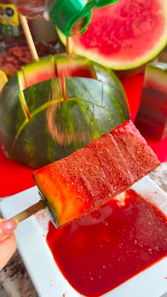 Watermelon slice on a stick coated in red chili powder and seasoning.