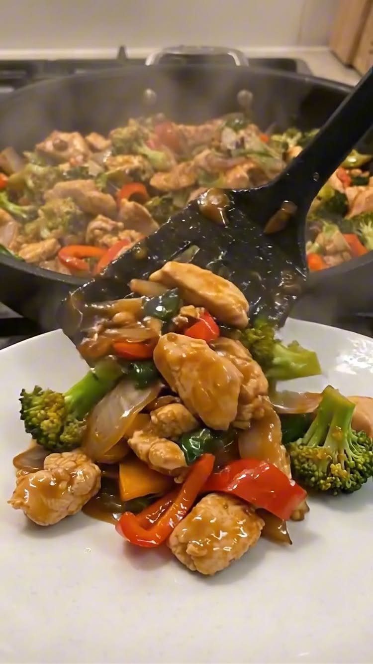 Glazed chicken with broccoli and red peppers served from a skillet onto a plate