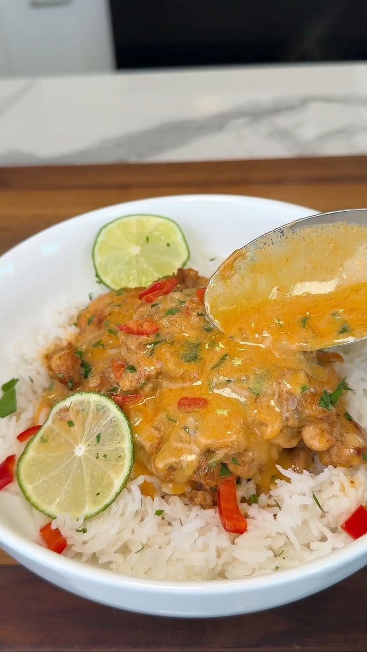 Creamy chickpea curry with red peppers and lime slices served over white rice.