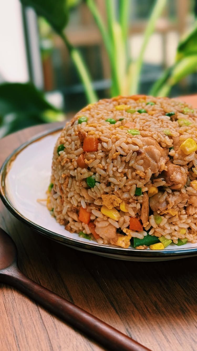 Fried rice with chicken, carrots, and peas served on a white plate.