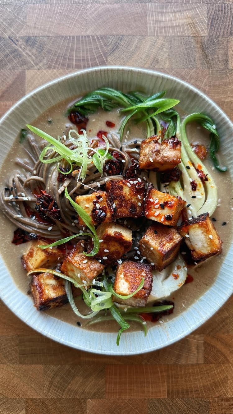 Soba noodles with seared tofu, bok choy, and sesame seeds in a bowl.
