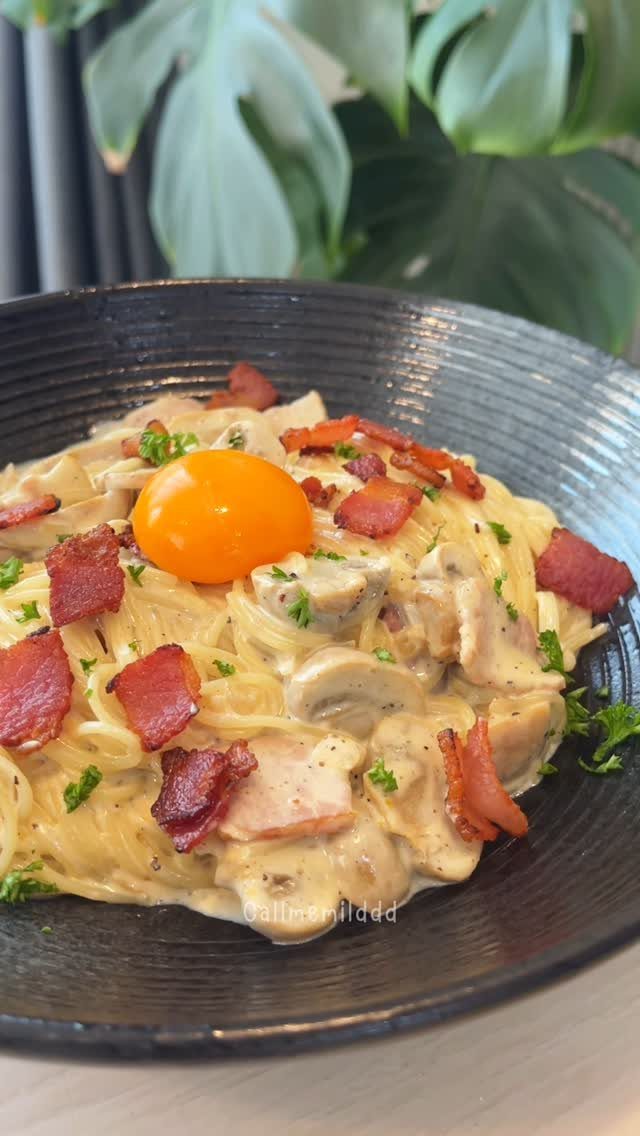 Creamy pasta with bacon and mushrooms topped with a raw egg yolk