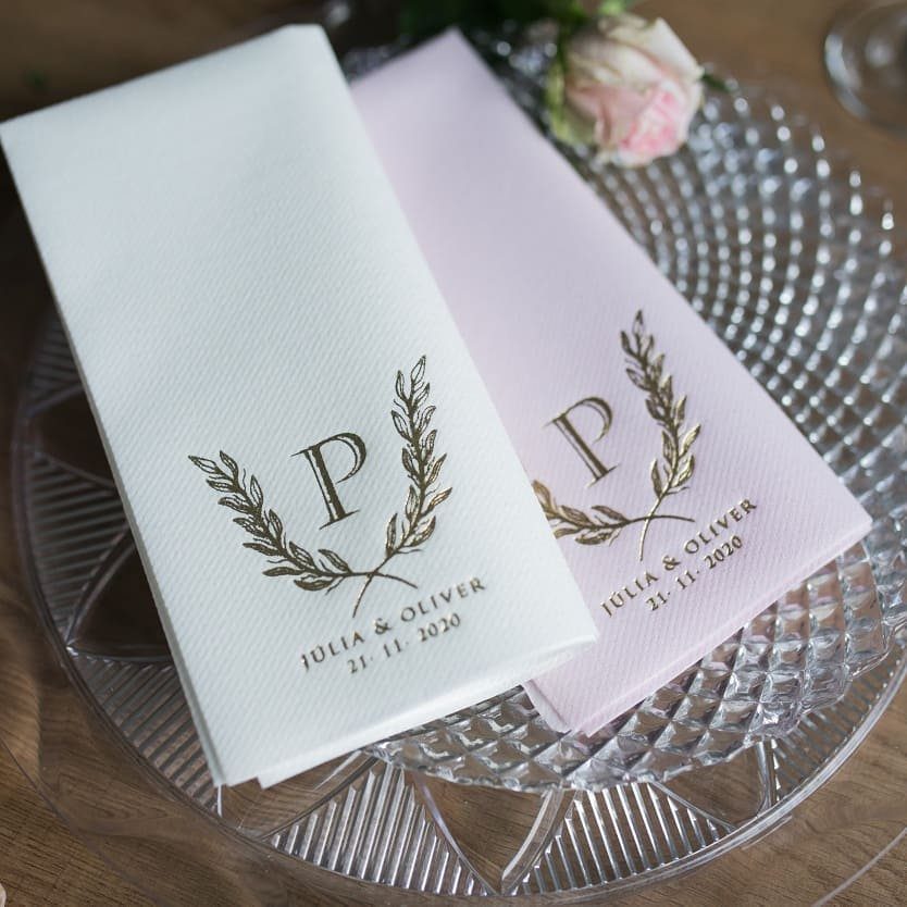 White and pink napkins with gold personalized monograms on a glass plate