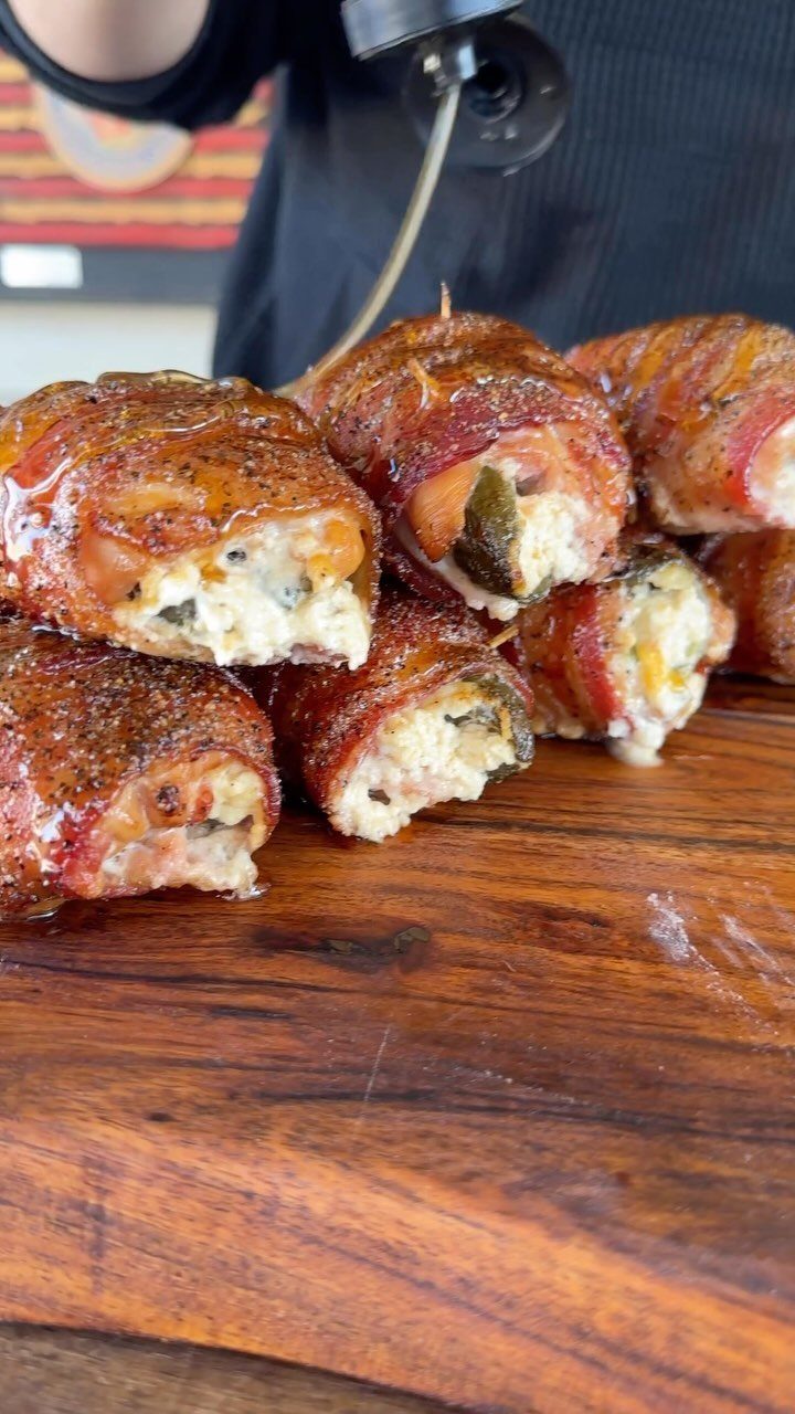 Bacon-wrapped jalapeño poppers filled with melted cheese on a wooden serving board.