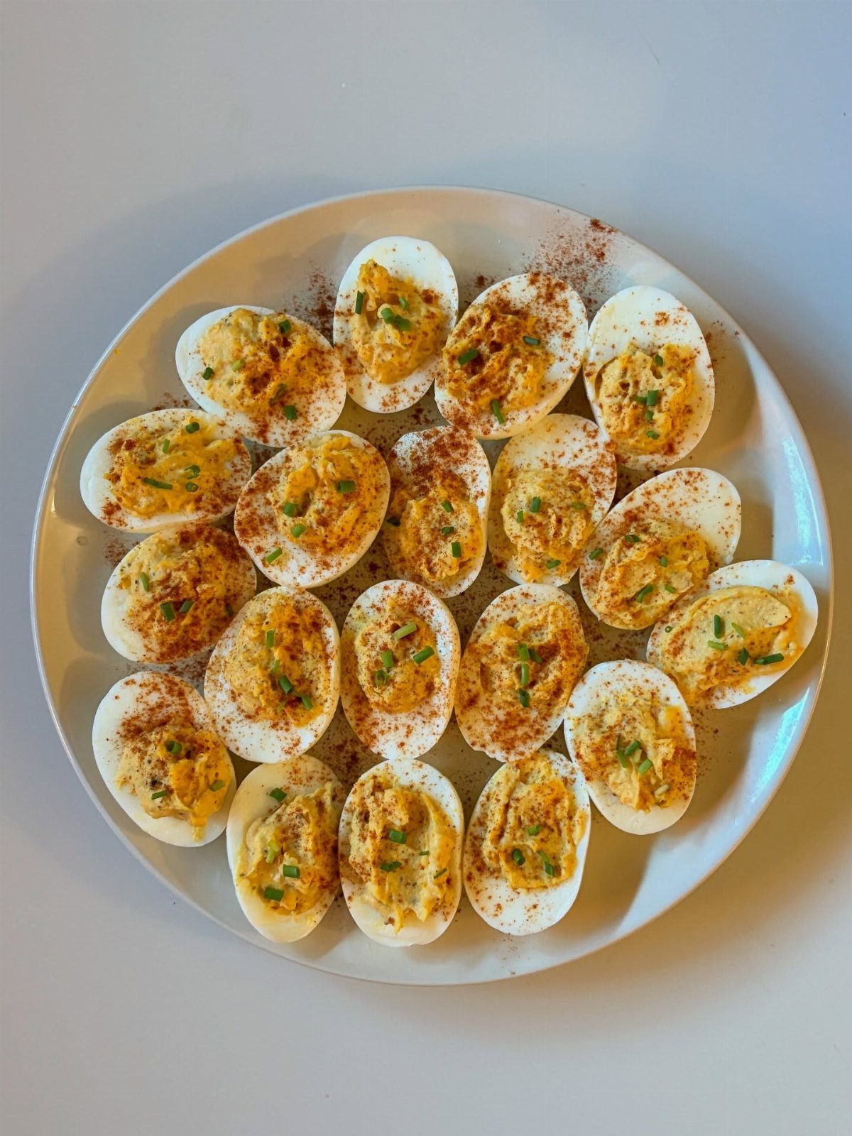 Deviled eggs with creamy yolk filling and chives on a white plate