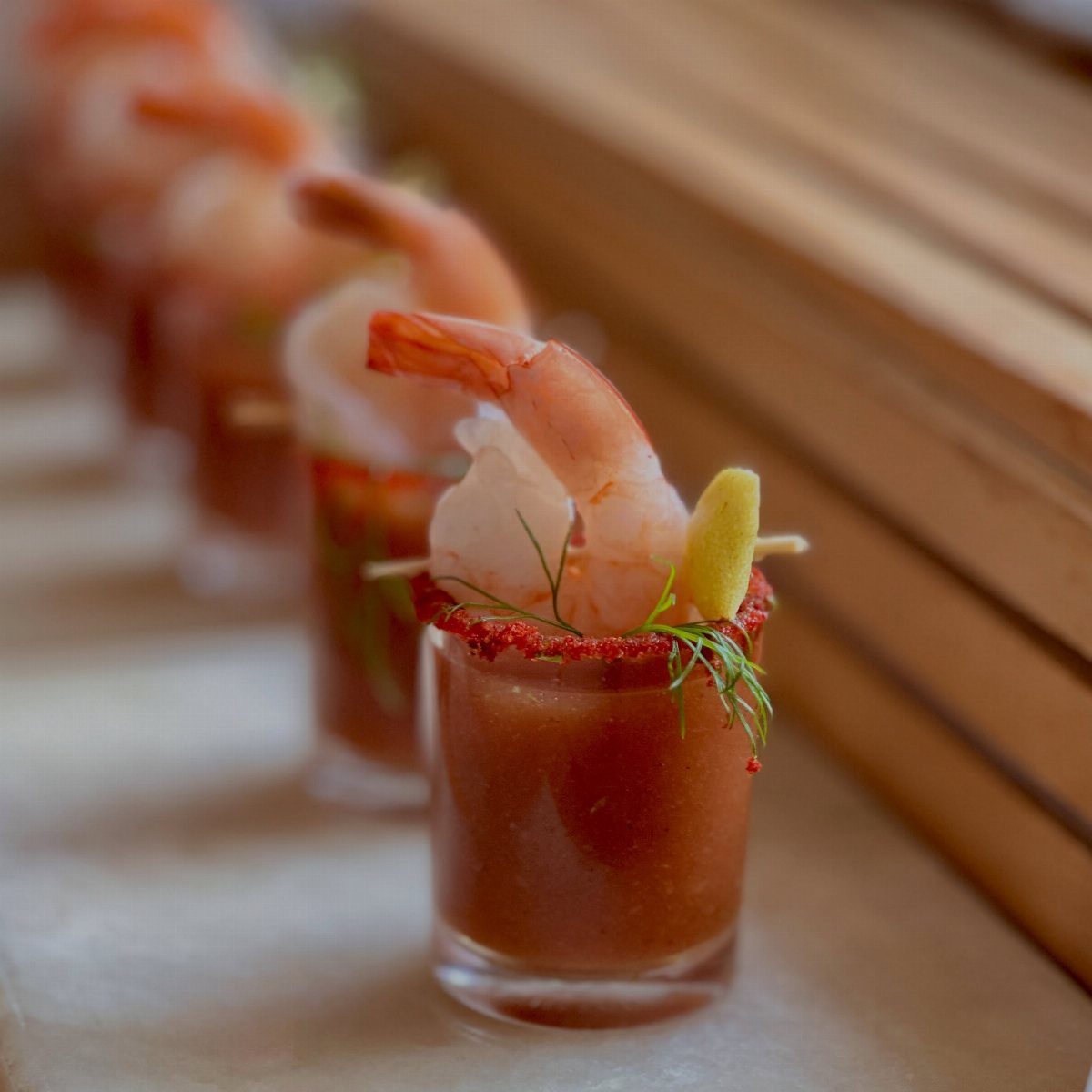 Prawn cocktails in small glasses with red sauce, lemon, and fresh dill.