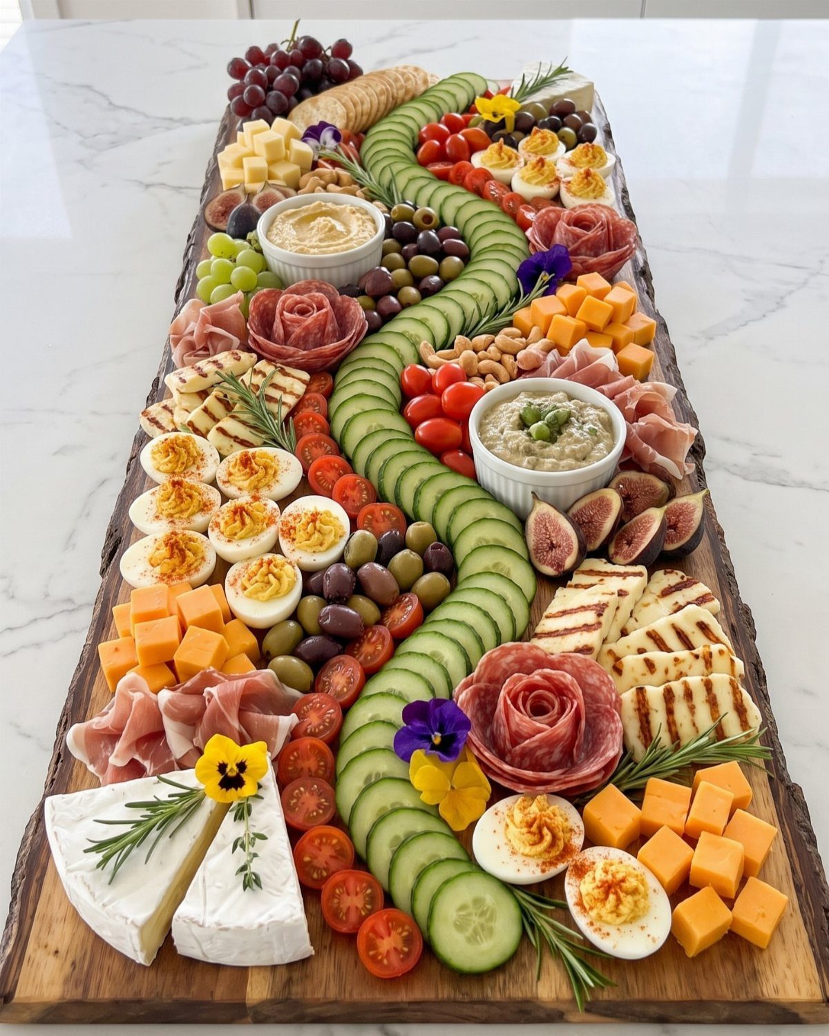 Large wooden platter with assorted cheeses, fruits, vegetables, meats, and deviled eggs.