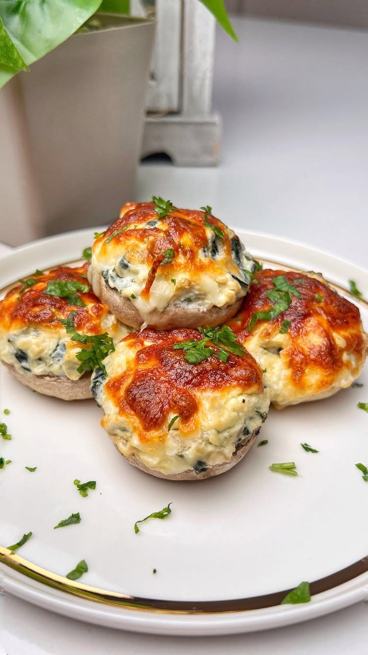 Stuffed mushrooms topped with melted browned cheese and fresh parsley on a white plate