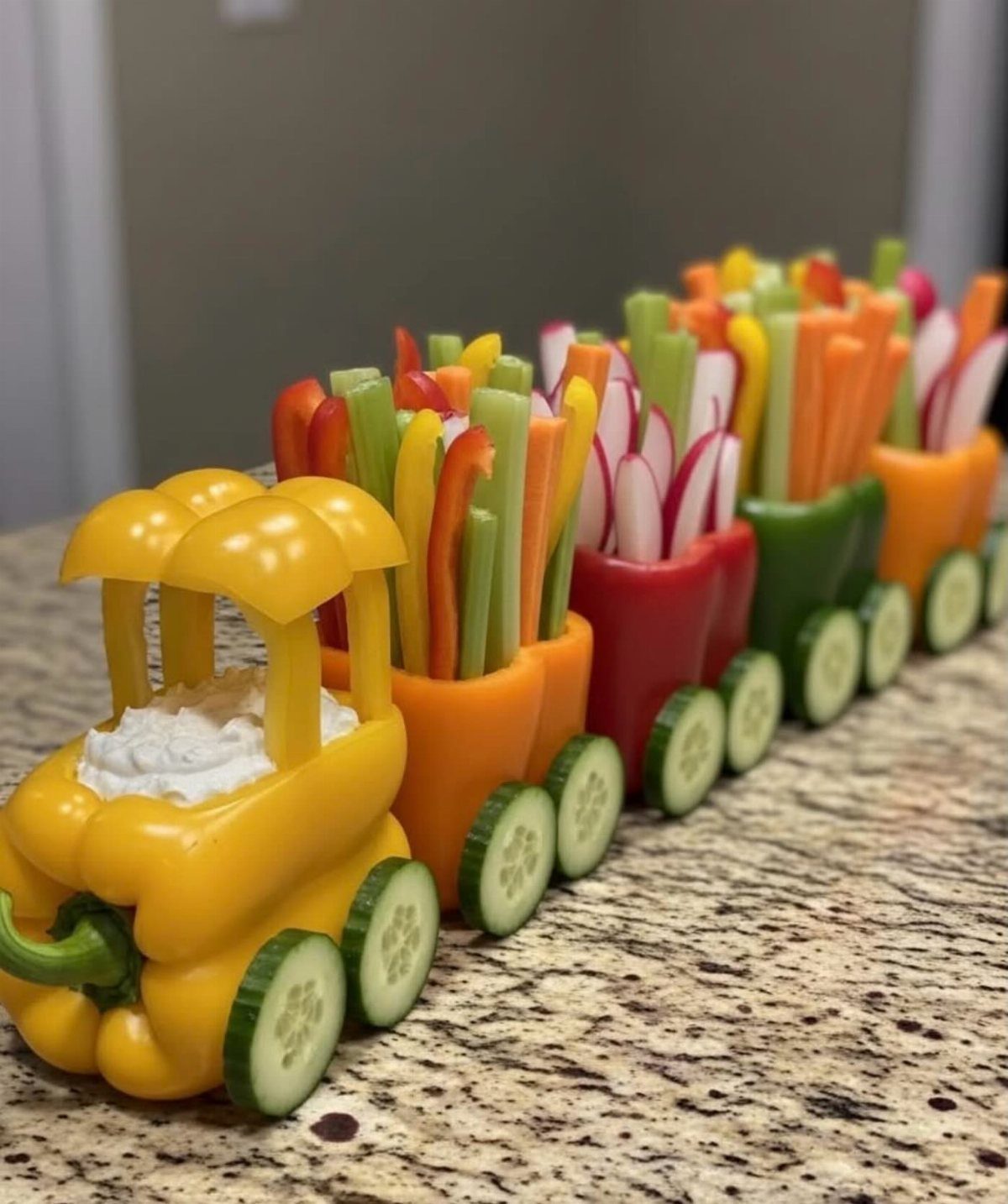 Vegetable tray arranged as a train using bell peppers, carrots, celery, and cucumbers.