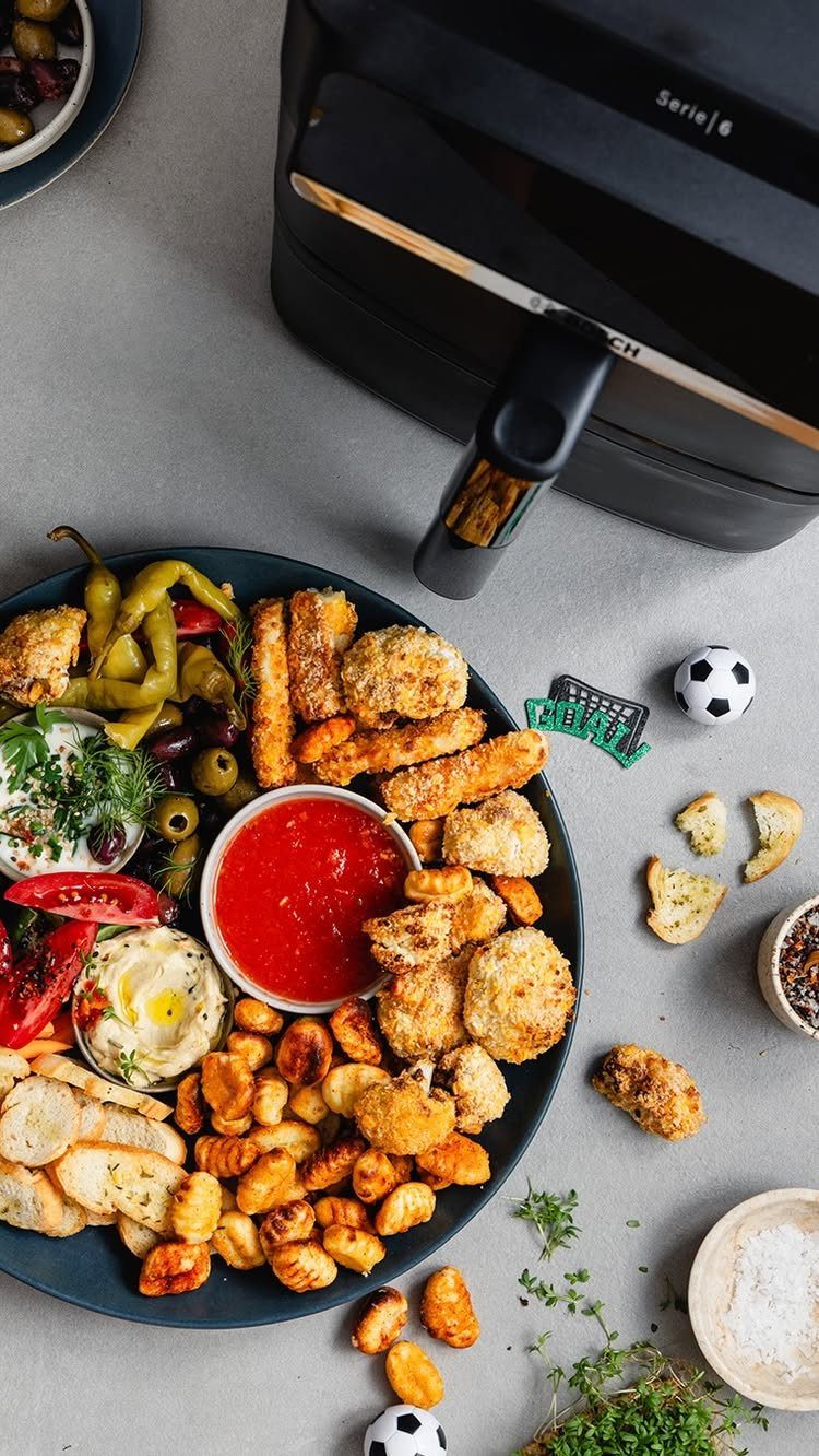 Platter of fried chicken and appetizers with small soccer balls on grey background