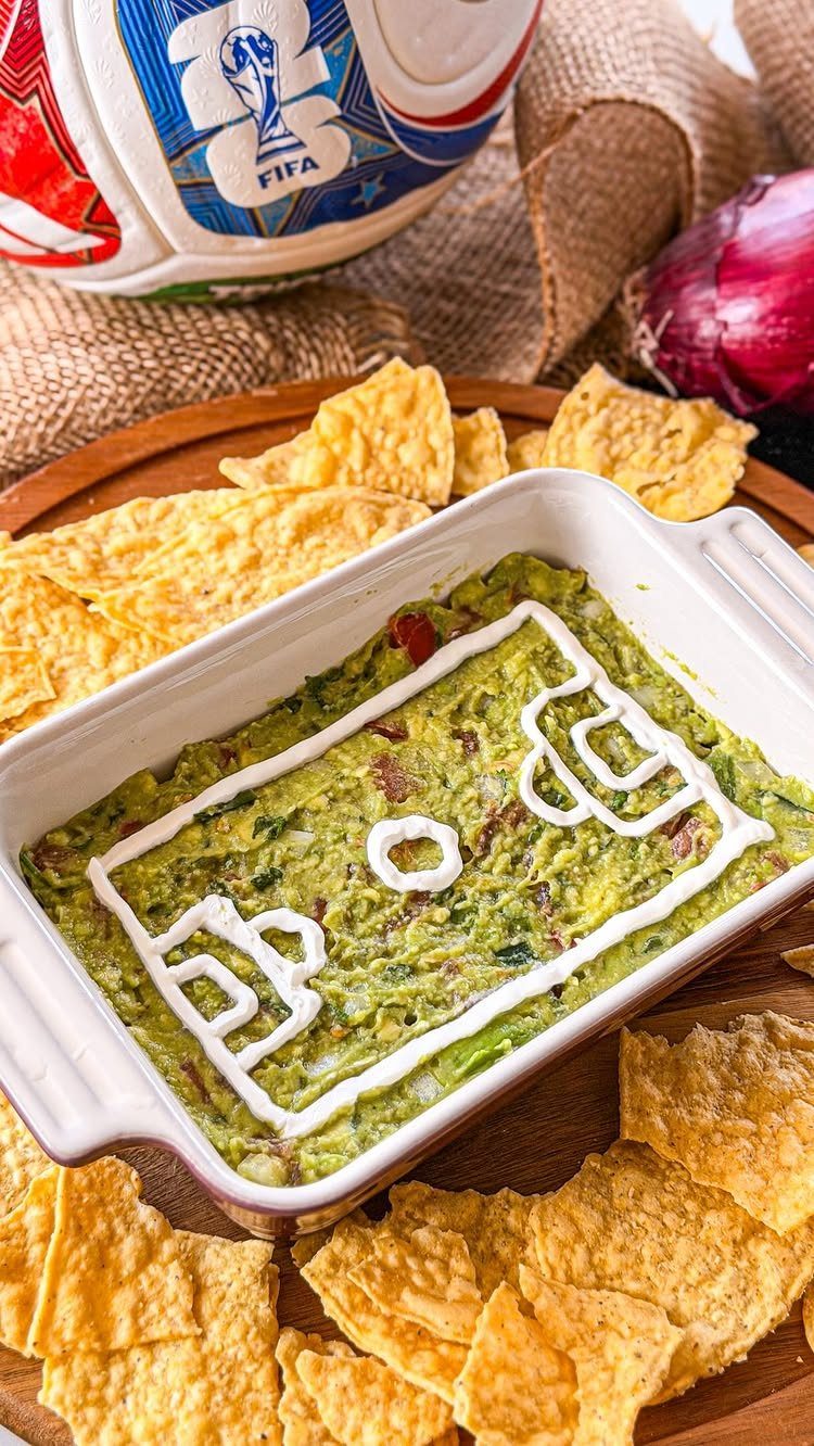 Guacamole in a white dish decorated as a soccer field with tortilla chips.